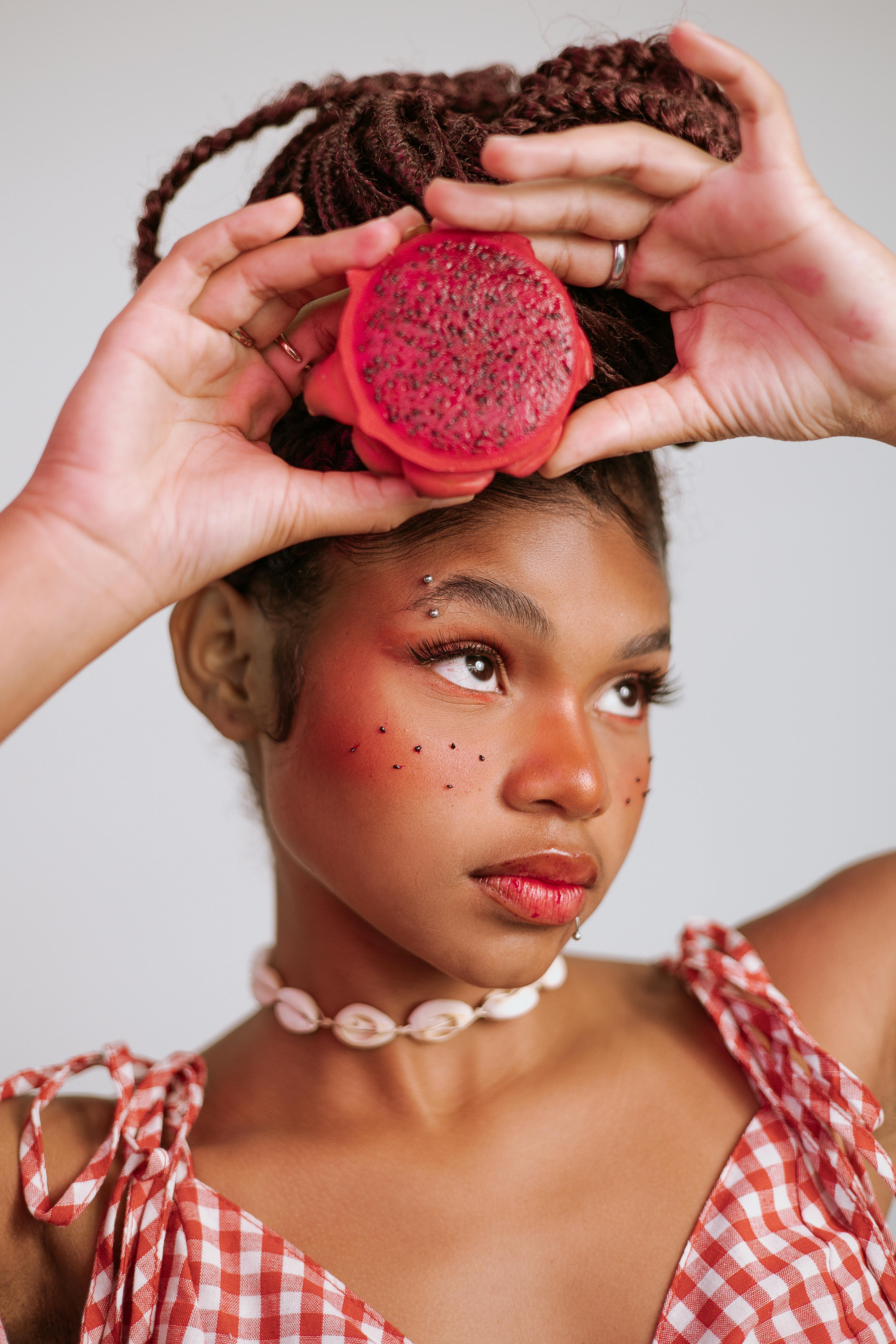 Young woman with dragon fruit posing in vibrant, stylish fashion portrait.
