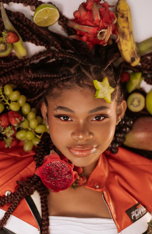 Free Colorful portrait of a woman surrounded by diverse fruits, showcasing fashion and freshness. Stock Photo