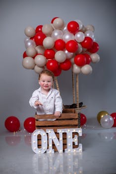 Adorable first birthday setup with balloons and illuminated ONE sign.