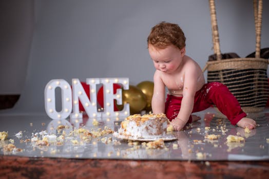 Cute baby enjoying a one-year birthday cake smash indoors.