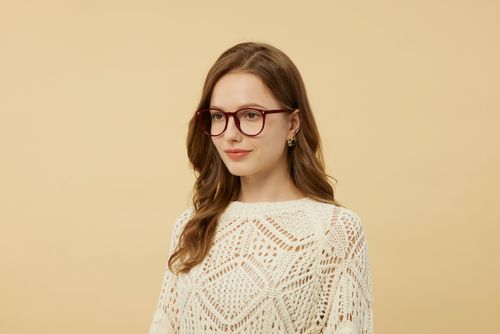 Free Stylish woman wearing red glasses and a white lace top in a studio portrait. Stock Photo