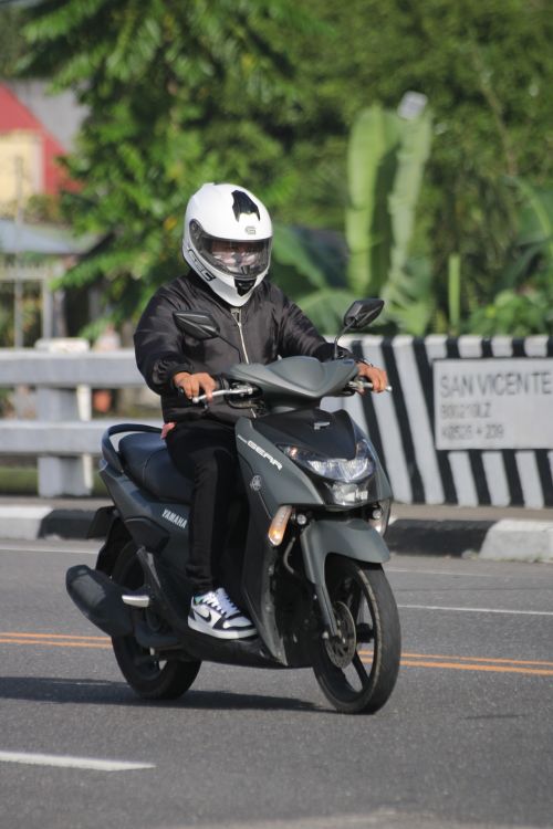 Free Person in helmet riding a scooter on city street in daylight. Stock Photo