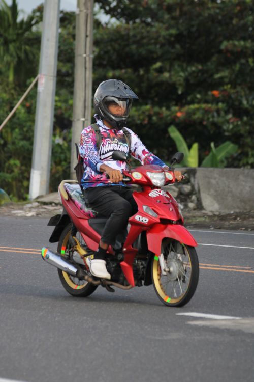 Free Motorcyclist in helmet riding red motorbike on a suburban road. Stock Photo