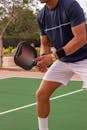 Athlete playing pickleball outdoors with paddle and ball on court