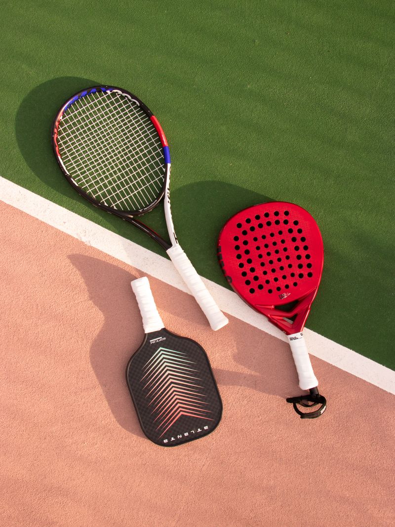 Padel and pickleball rackets side by side on a court