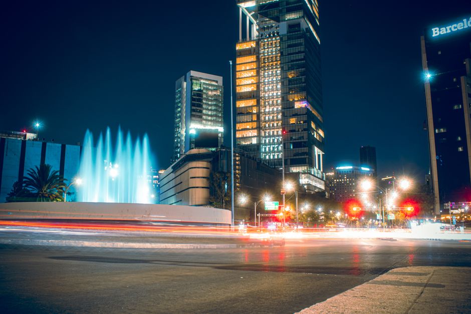 Vibrante larga exposición del moderno horizonte de Ciudad de México con fuentes iluminadas y tráfico bullicioso.