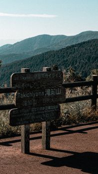 A scenic mountain view with a wooden signpost at Izu Skyline, Japan.