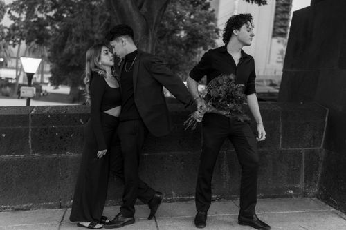 Free A captivating black and white shot of three adults in an urban setting with contrasting emotions. Stock Photo