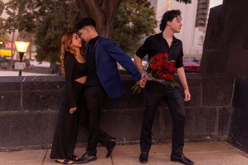 Free Three people caught in emotional love triangle outdoors at sunset. Stock Photo