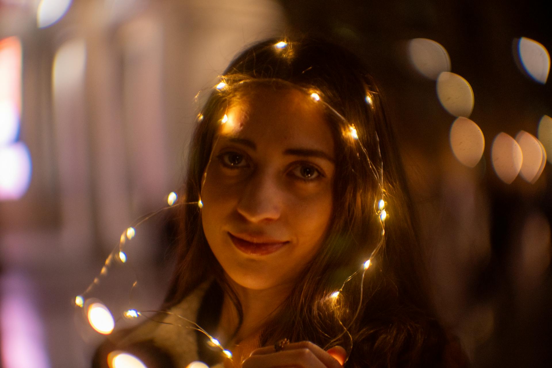 A captivating night portrait of a woman adorned with glowing string lights, creating a magical ambiance.