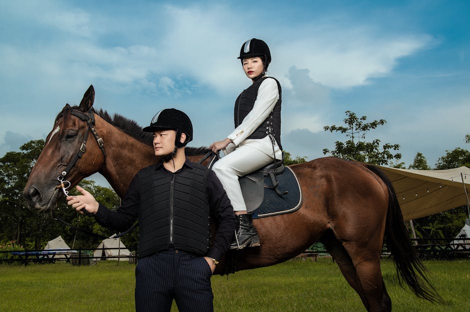 Professional equestrian holding a horse with a rider atop, poised in modern riding gear outdoors.
