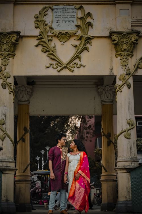 Free A joyful couple in traditional Indian attire under an ornate archway in Kolkata, India. Stock Photo