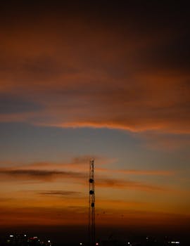 Telecommunication tower silhouette against a vibrant Bengaluru sunset sky, capturing the city's golden hour.