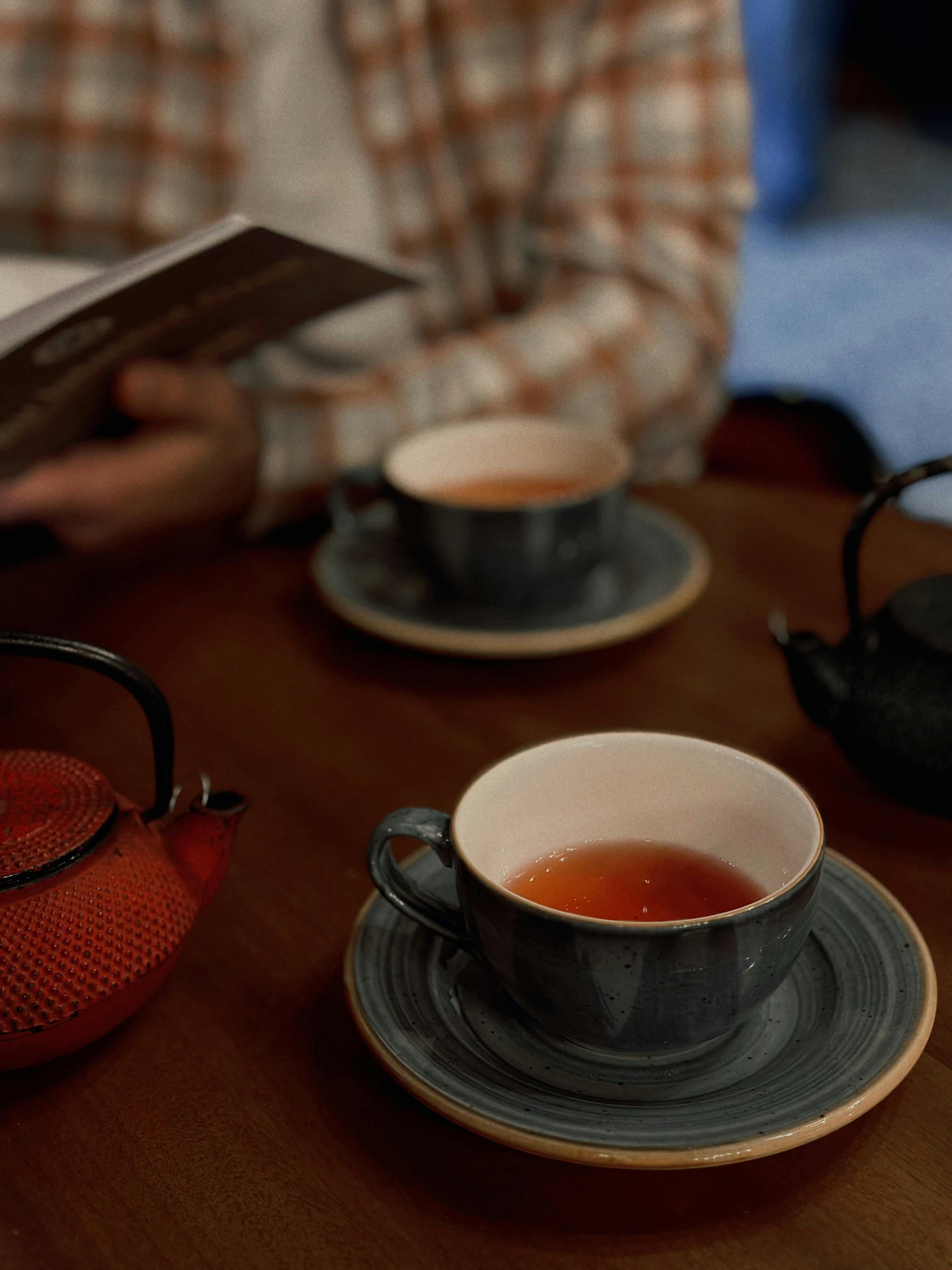 Warm cafe ambience with tea cups and teapots on a wooden table.