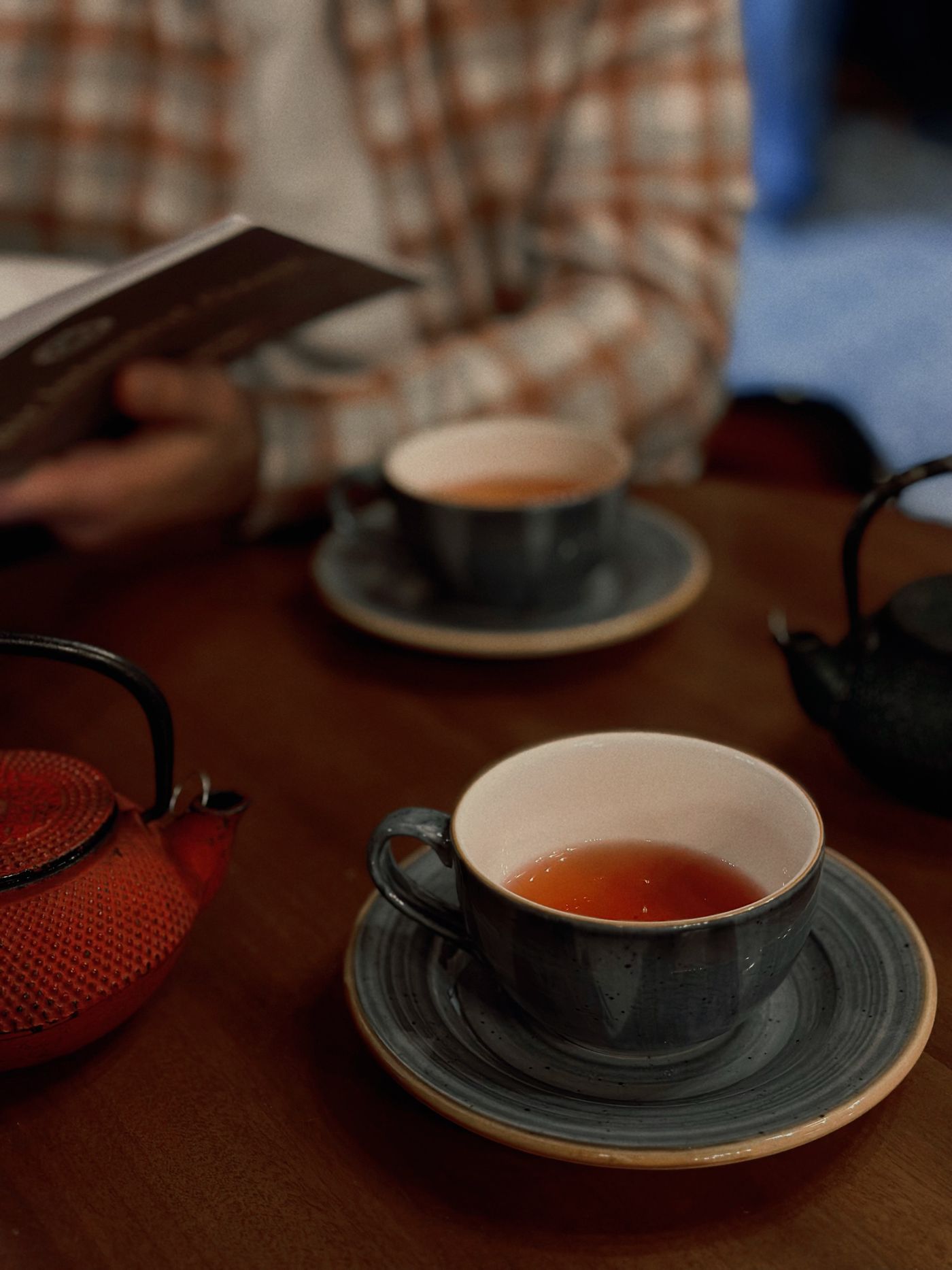 Warm café table with freshly brewed tea, ceramic tea cups and teapots