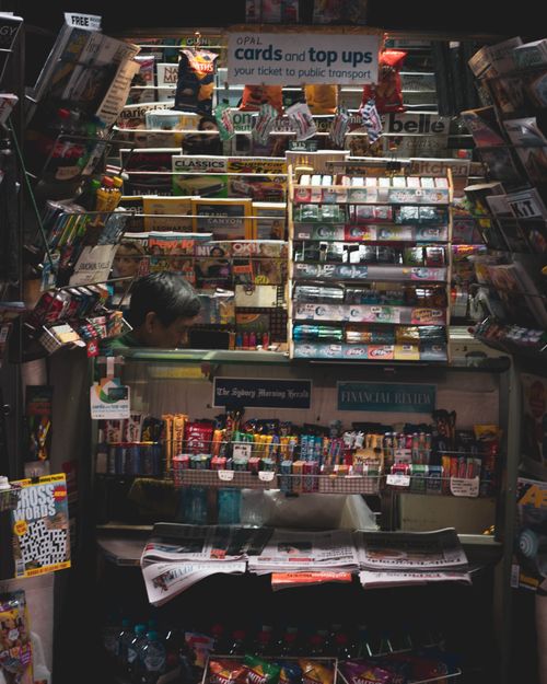 Free Vibrant newsstand filled with magazines, snacks, and sundry items in a busy urban setting. Stock Photo