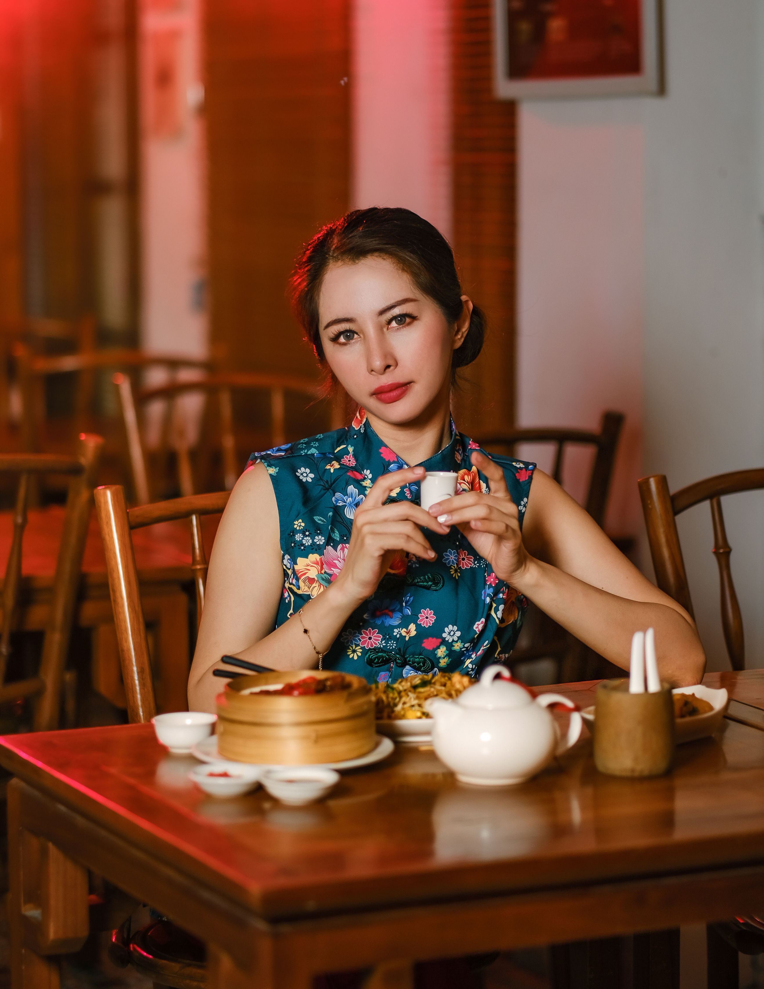 Portrait of a stylish woman in traditional attire enjoying tea at a Jakarta restaurant.