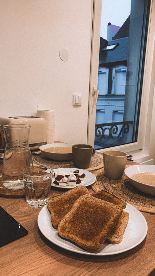 Free Warm breakfast scene featuring toast, coffee, and urban window view for a homely vibe. Stock Photo