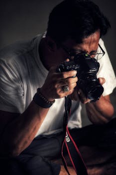 A dedicated photographer engrossed in his craft with a DSLR camera.