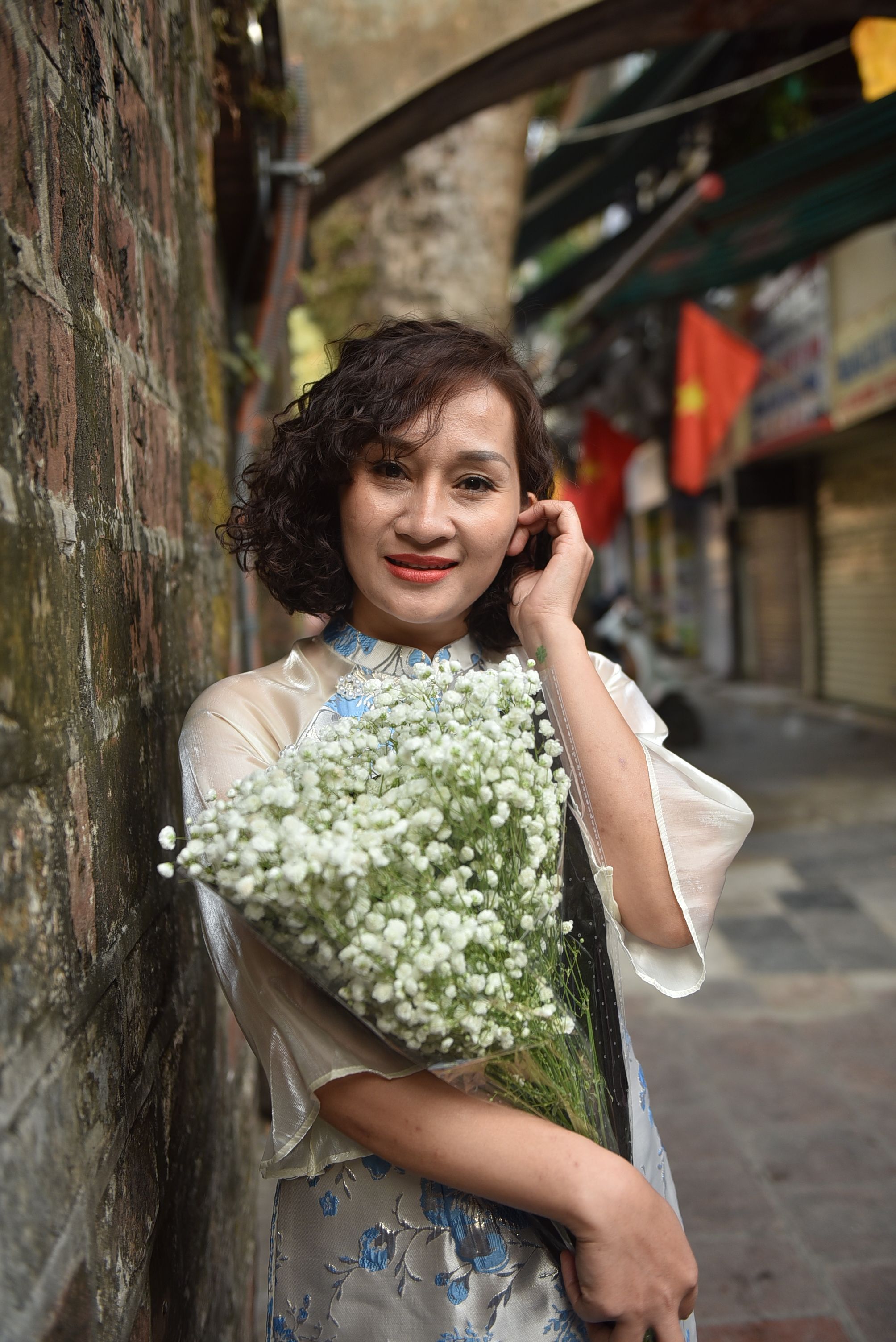 Woman Holding Flowers in a Historic Street · Free Stock Photo