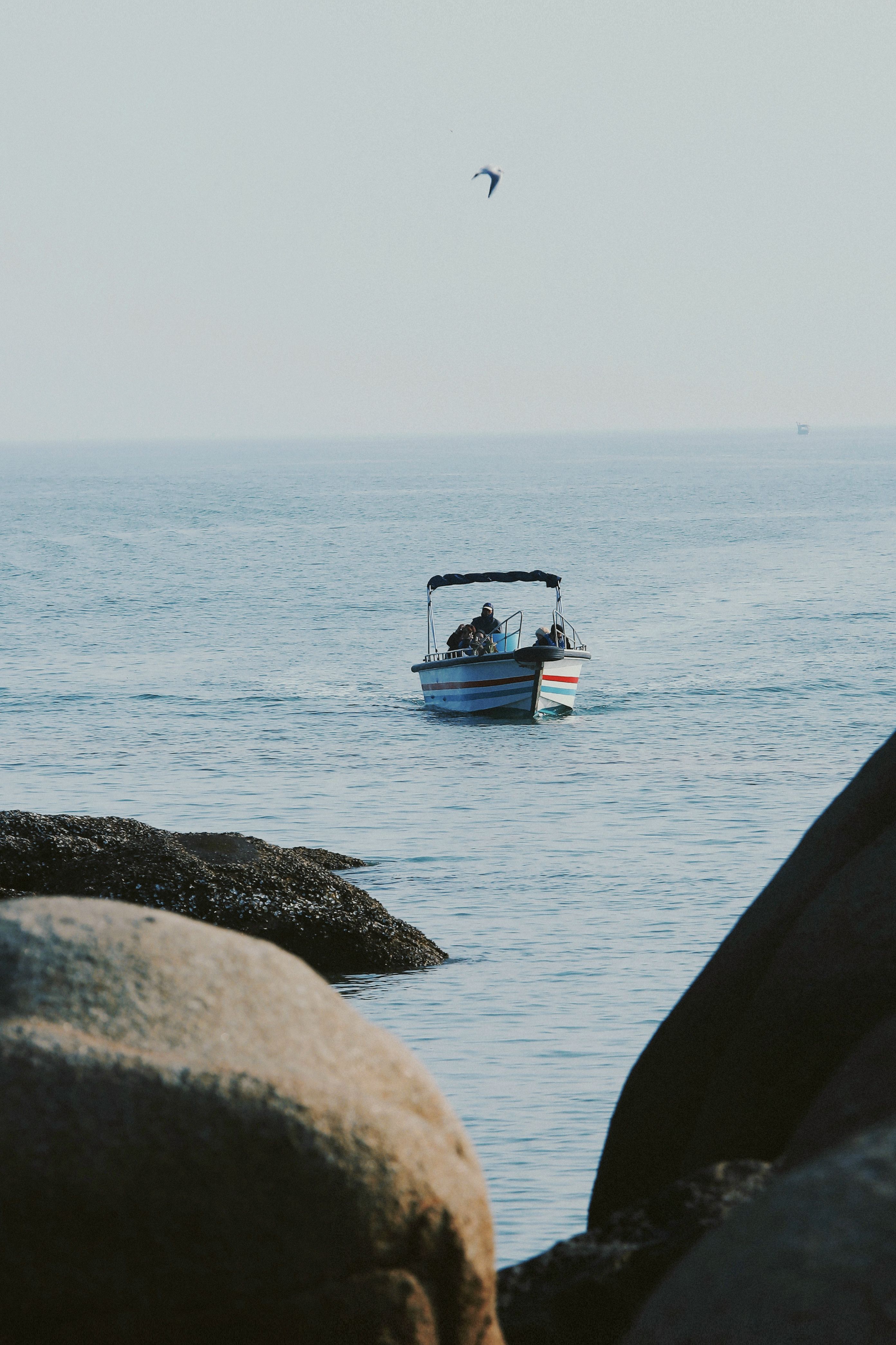 Serene Boat Ride on a Calm Sea Surrounded by Rocks · Free Stock Photo