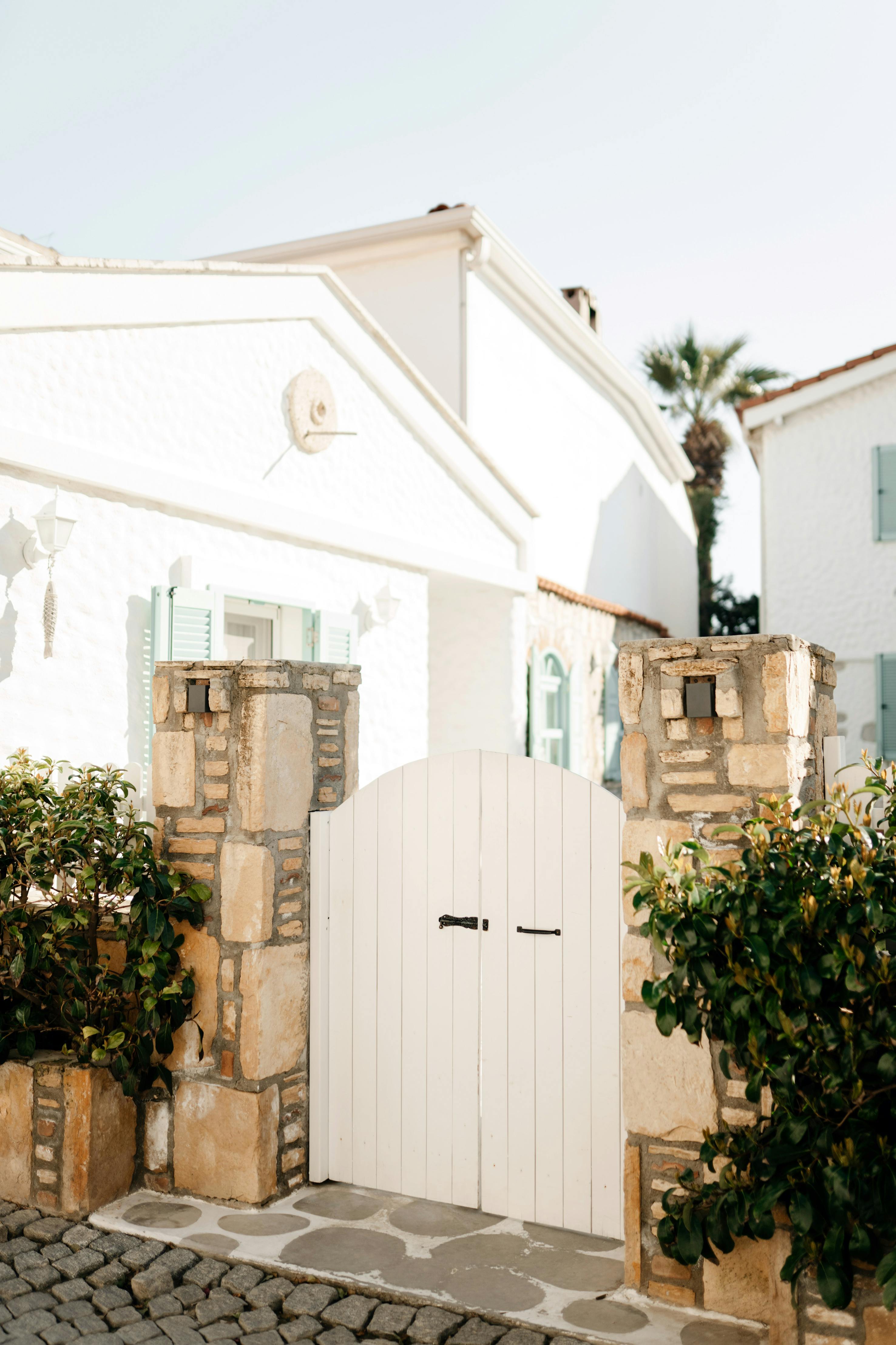 Quaint Mediterranean house entrance with a white gate, sunny ambiance.