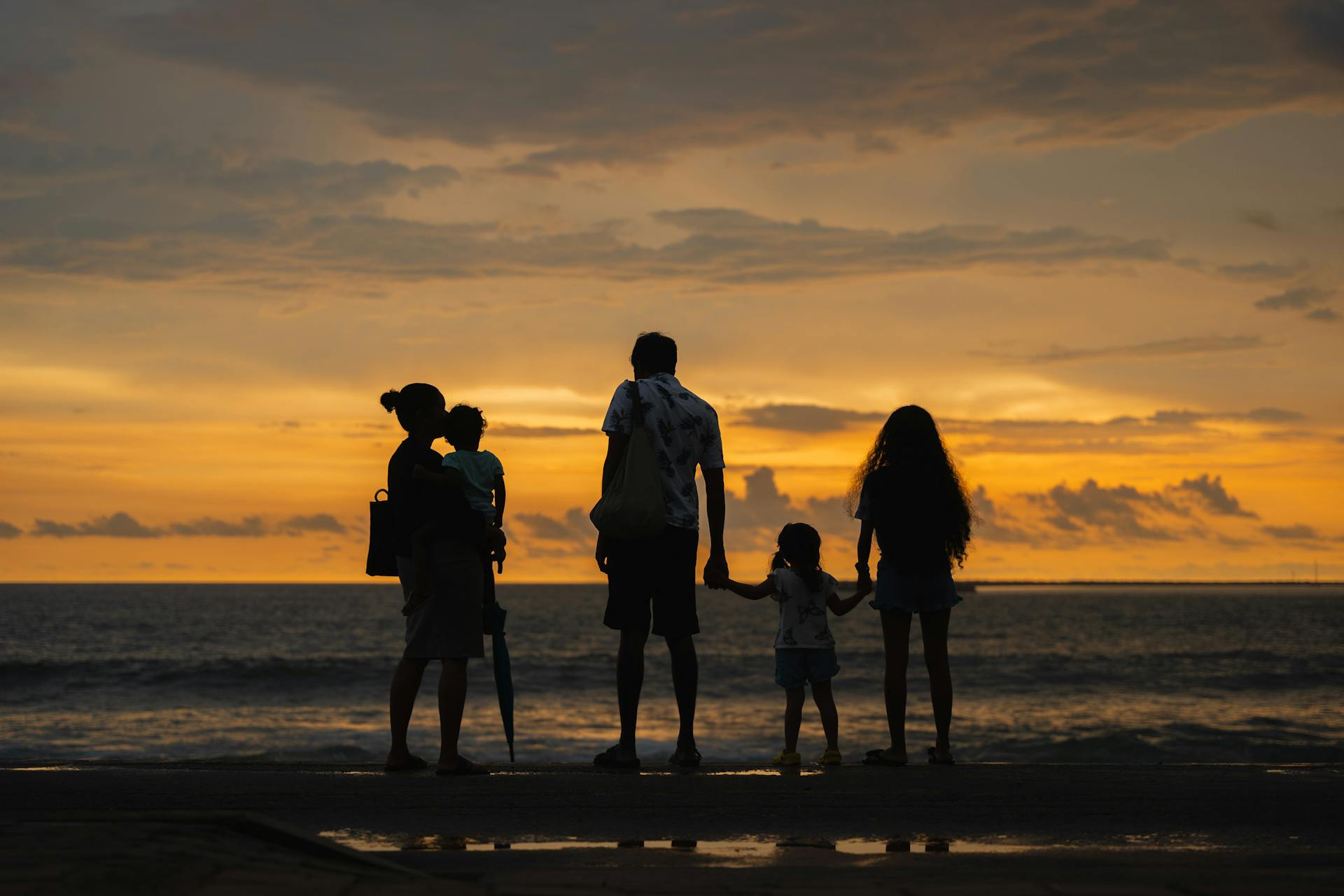 A family enjoying a serene sunset by the ocean at Colombo beach, Sri Lanka.