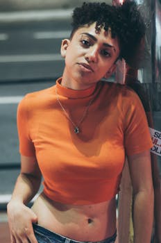 夜晚的城市里，一名年轻女子的肖像靠在一面橙色的墙上