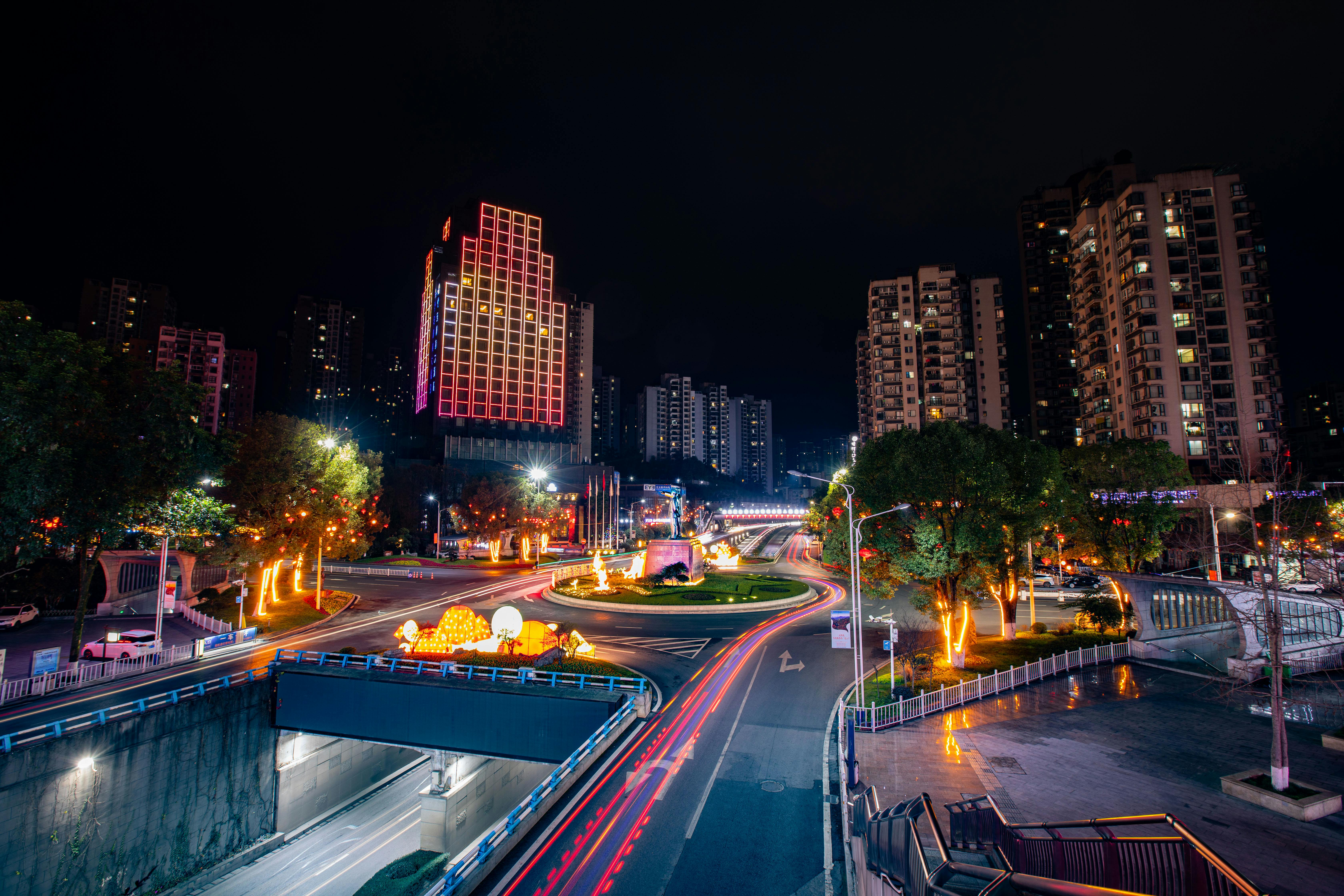 Cityscape at night with vibrant light trails and illuminated buildings.
