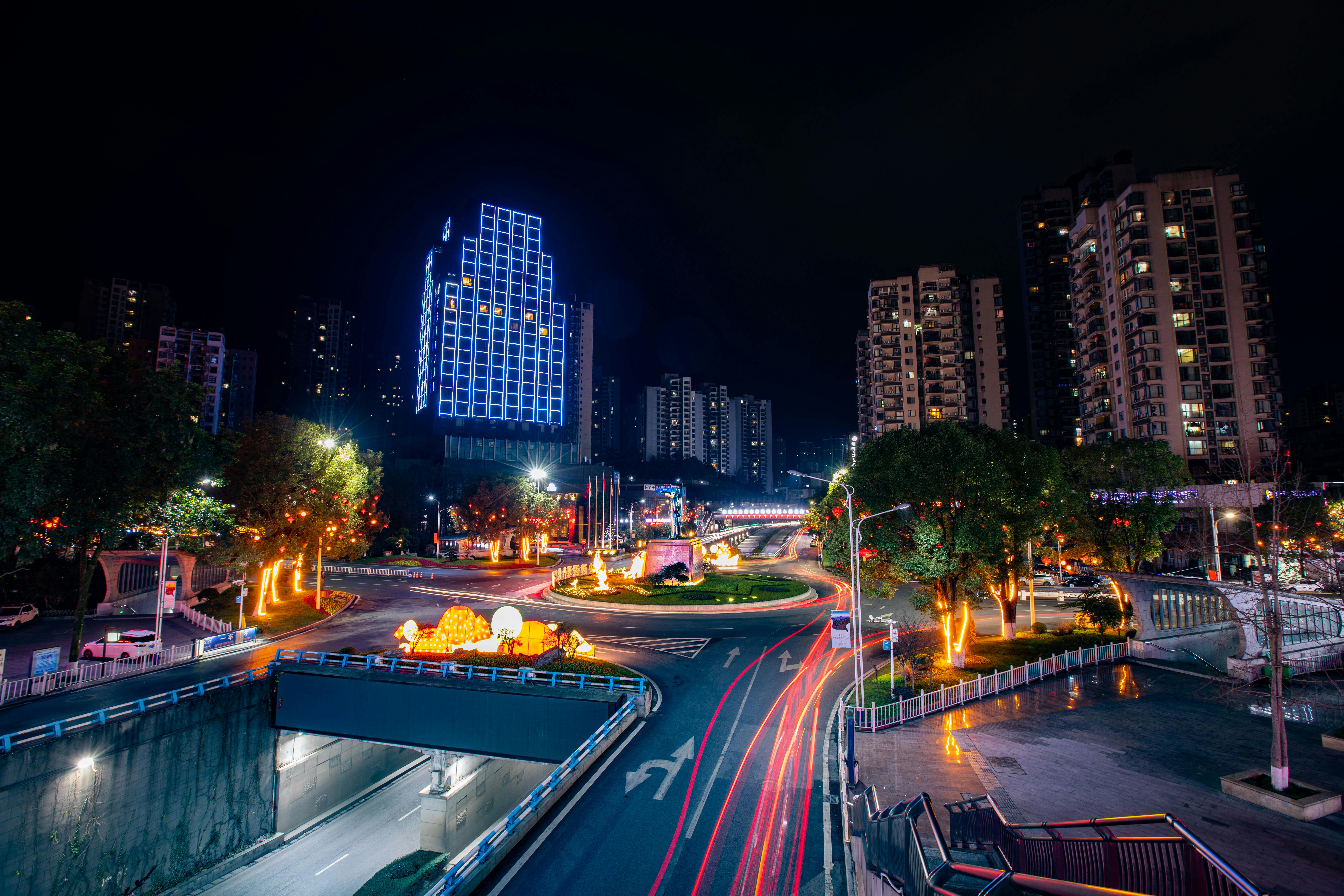Colorful cityscape at night with light trails and illuminated buildings, showcasing urban energy.