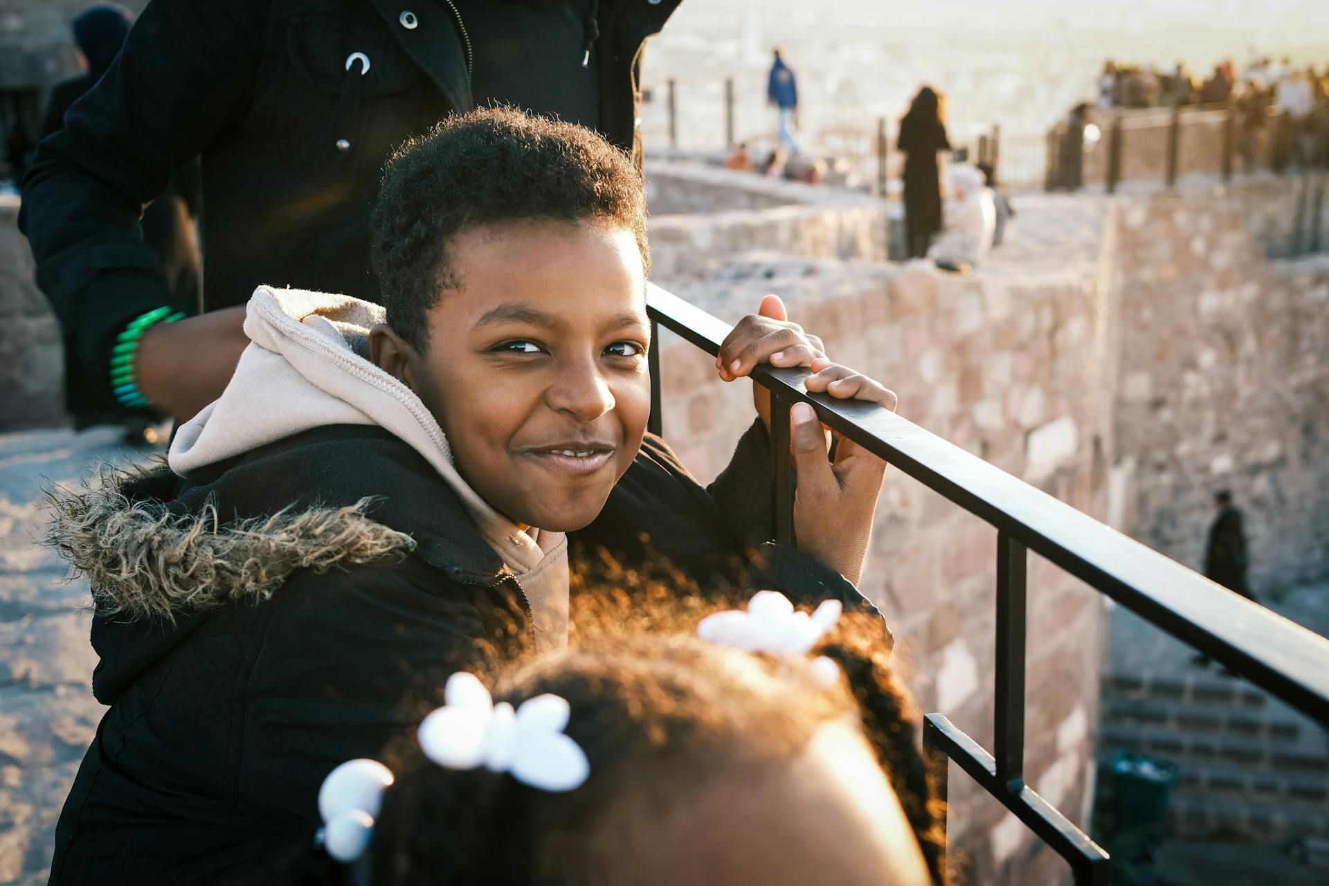 A smiling boy enjoys a sunny day at a historical fortress, creating a warm, inviting scene.