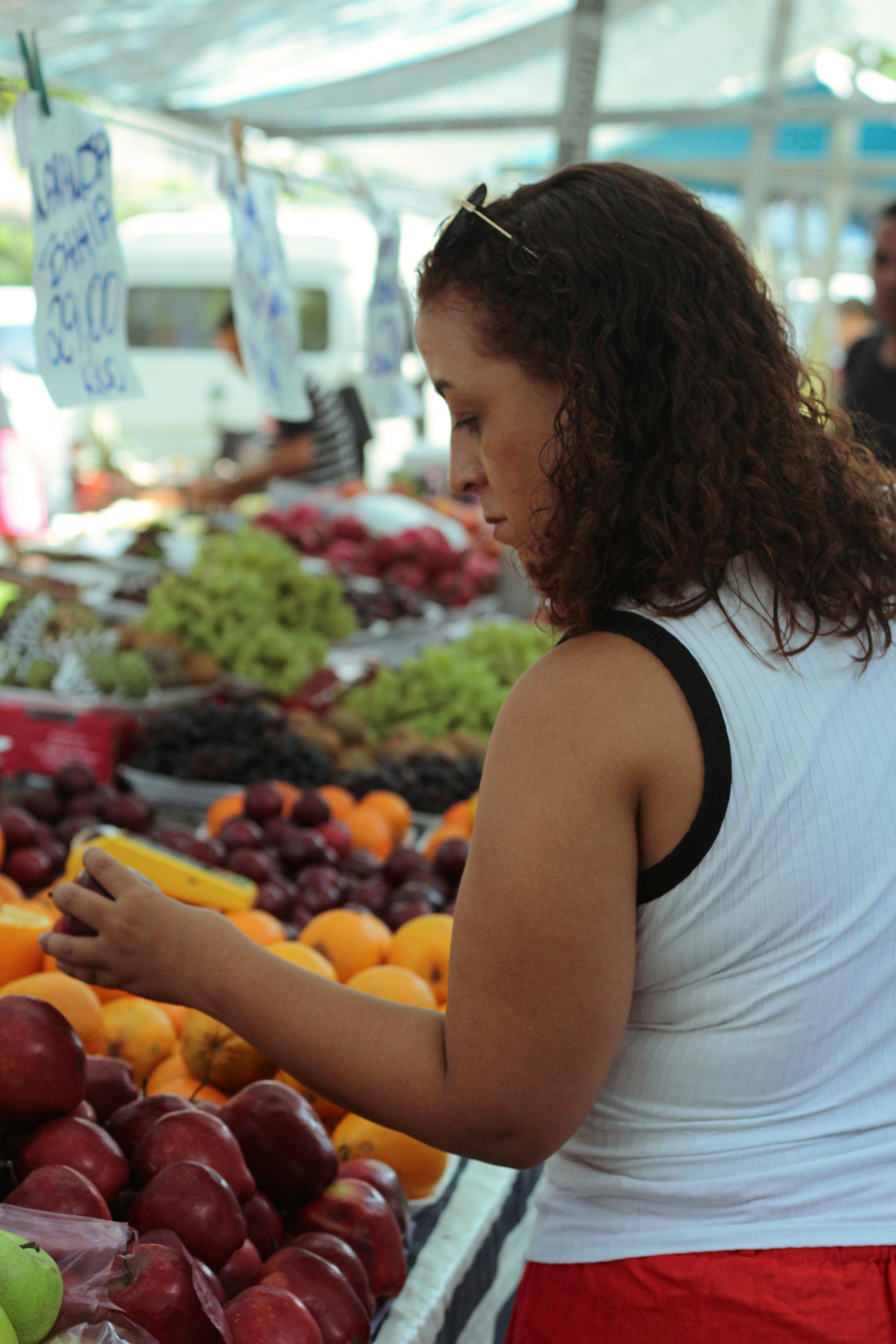 Woman shopping for fresh fruit at an outdoor market. Vibrant produce selection.
