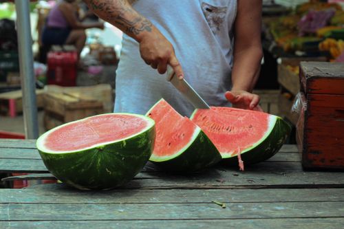 Free Sliced watermelon being prepared at an outdoor market. Stock Photo