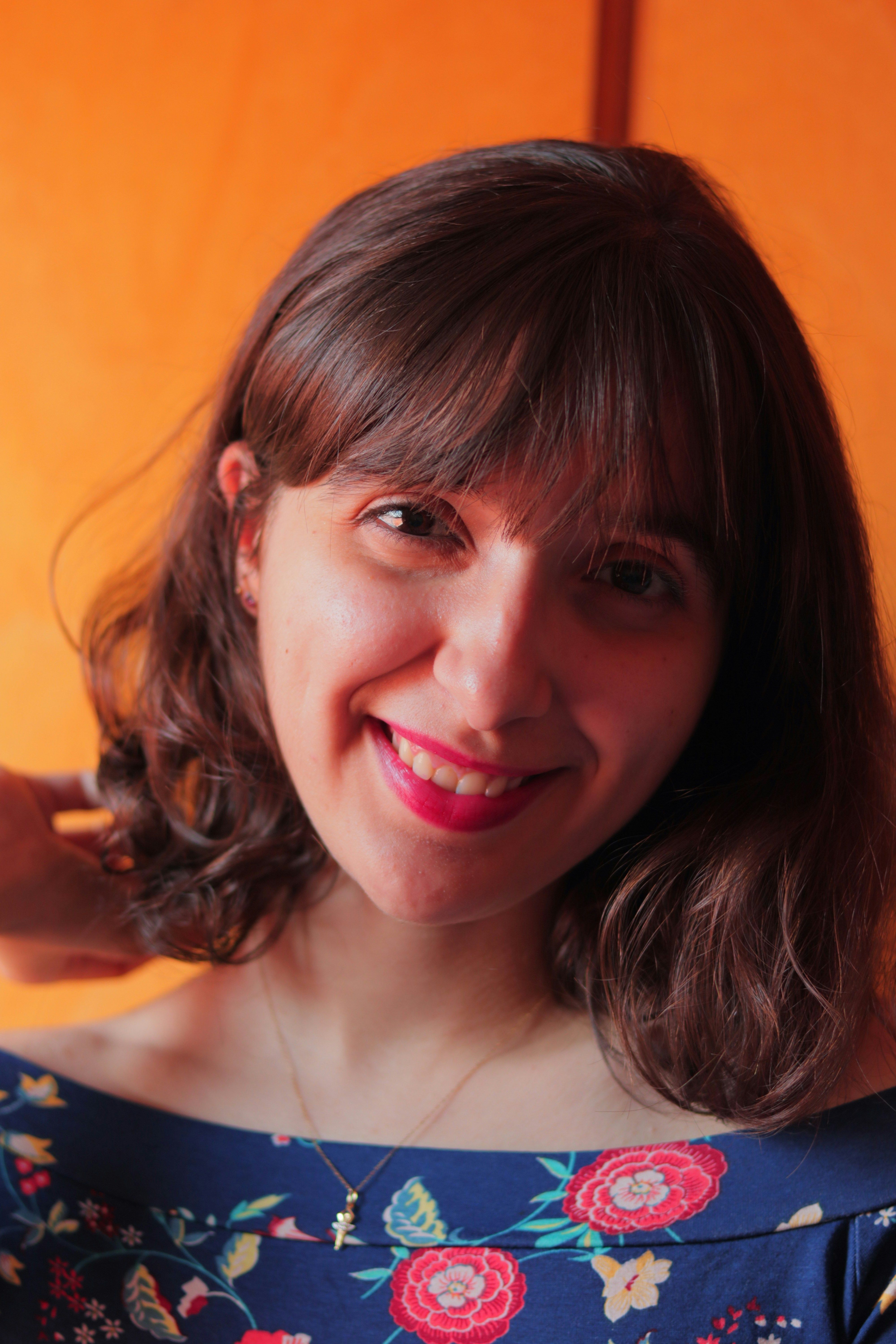 Portrait of a smiling woman wearing a floral dress indoors.