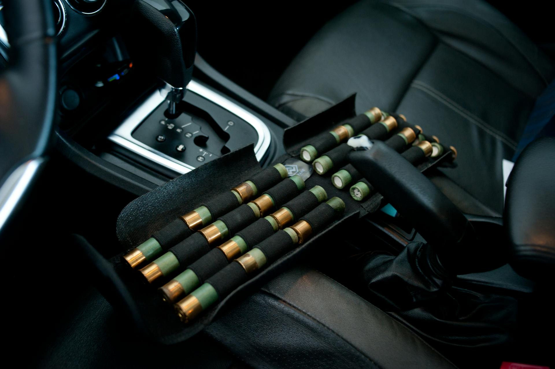 Shotgun shells organized in a car interior near the gearshift. Detailed vehicle close-up.