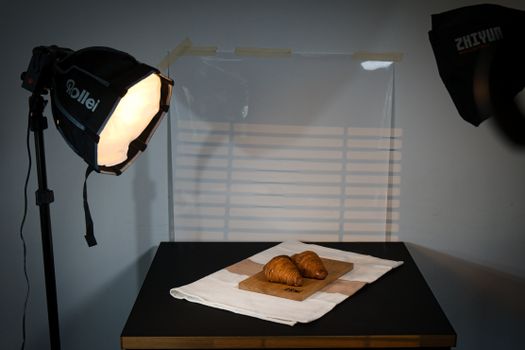 Studio setup featuring croissants on a table with professional lighting equipment.