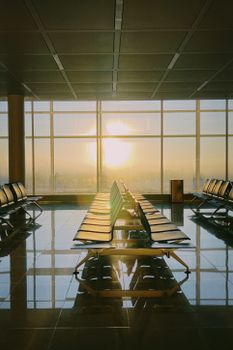 Empty airport seating area with stunning sunset view through large windows.