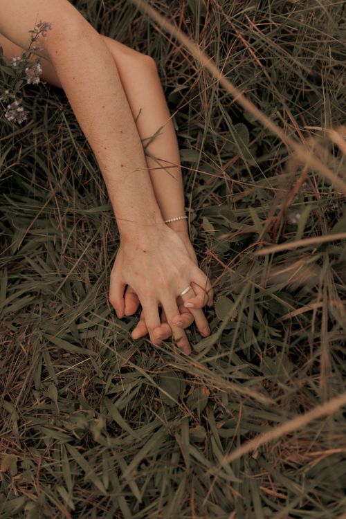 Free Couple holding hands in grassy field, capturing intimacy and connection. Stock Photo