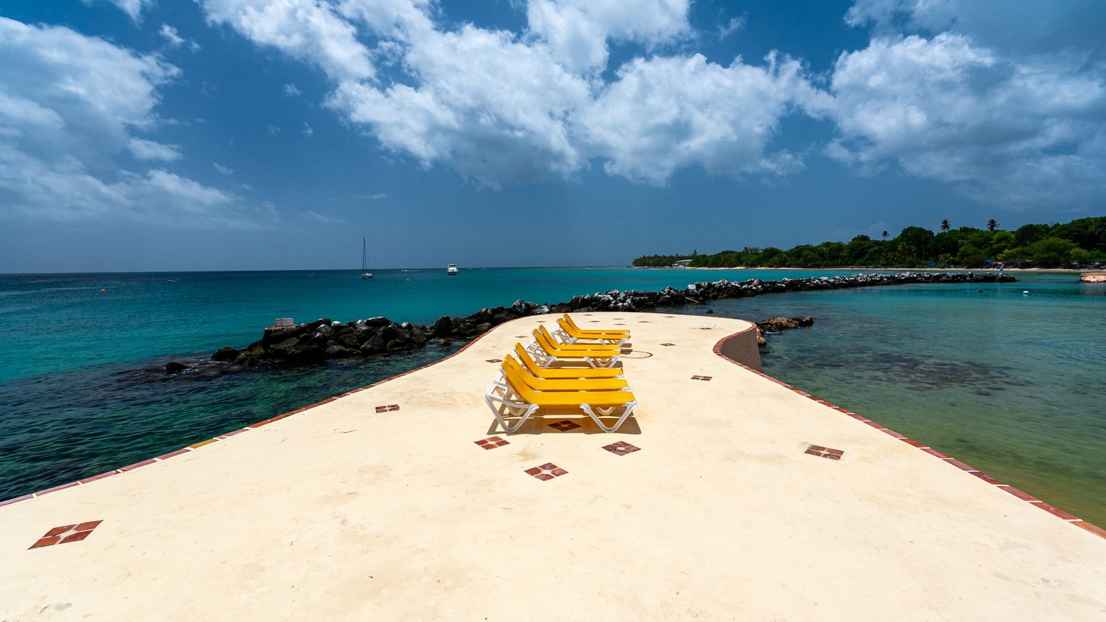 Relaxing beach scene with yellow chairs on a pier in Tobago, perfect for a tropical vacation.
