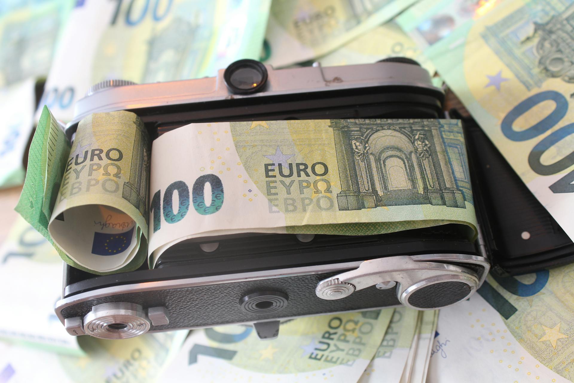 A vintage camera bundled with one hundred euro banknotes, symbolizing financial value.