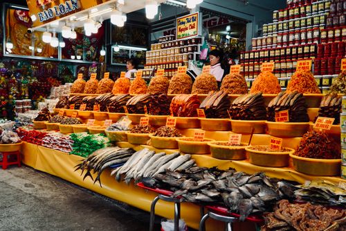Free Colorful assortment of dried goods and fresh fish at a bustling Vietnamese market stall. Stock Photo