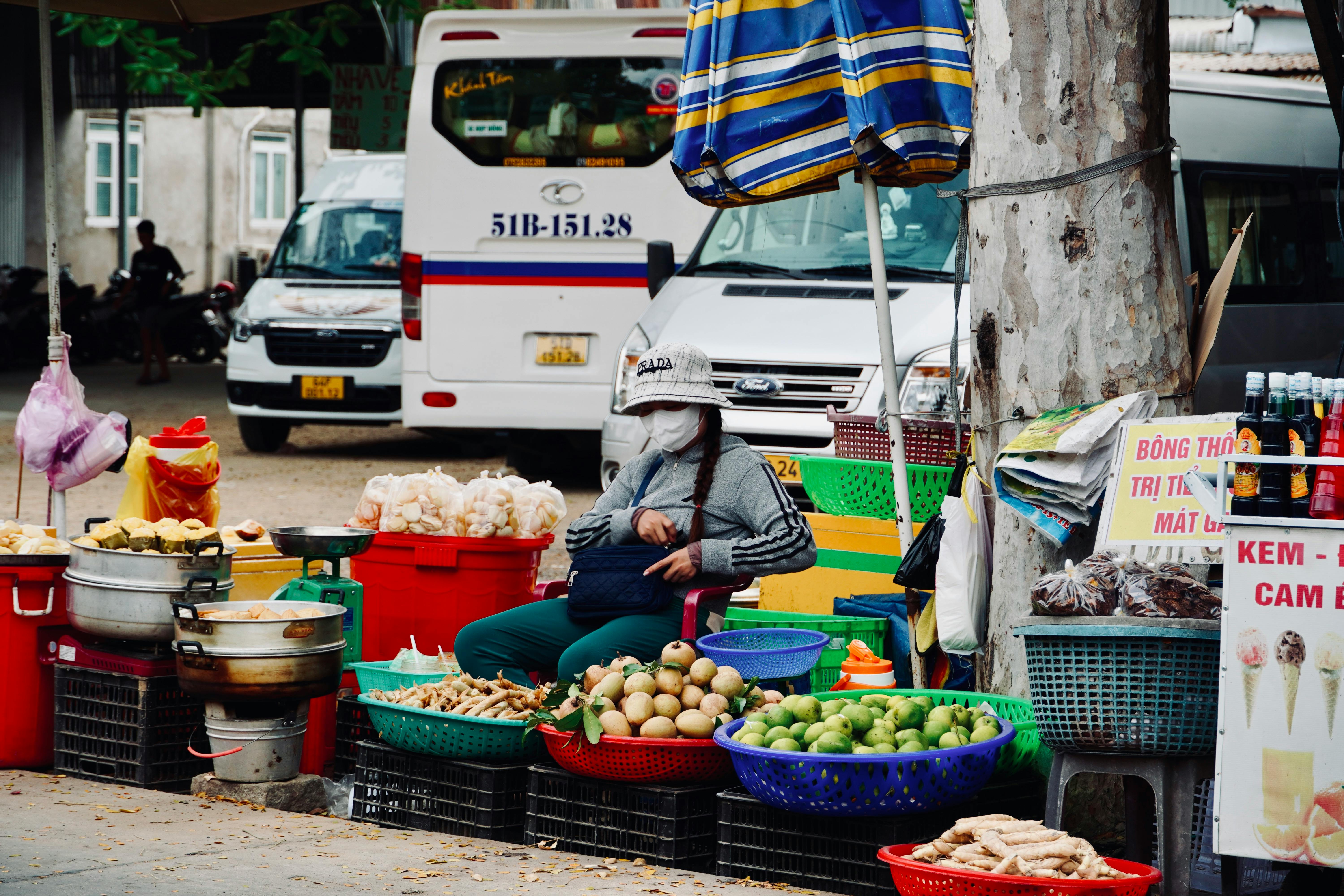 A vibrant street market scene featuring a fruit vendor in an urban setting in Vietnam.