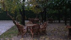 Tranquil garden scene with wooden chairs and tables surrounded by autumn foliage in Istanbul.