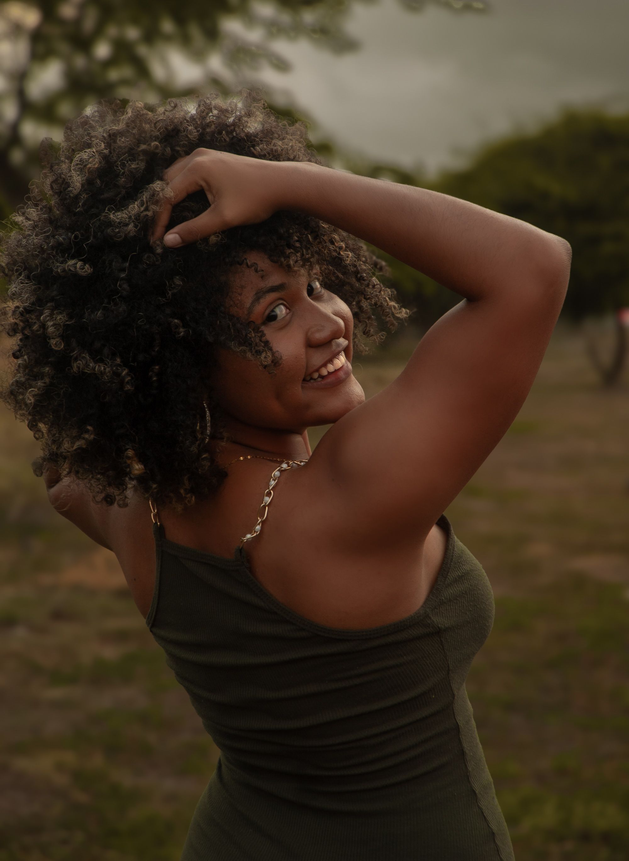 Smiling Woman with Curly Hair in Outdoor Setting · Free Stock Photo
