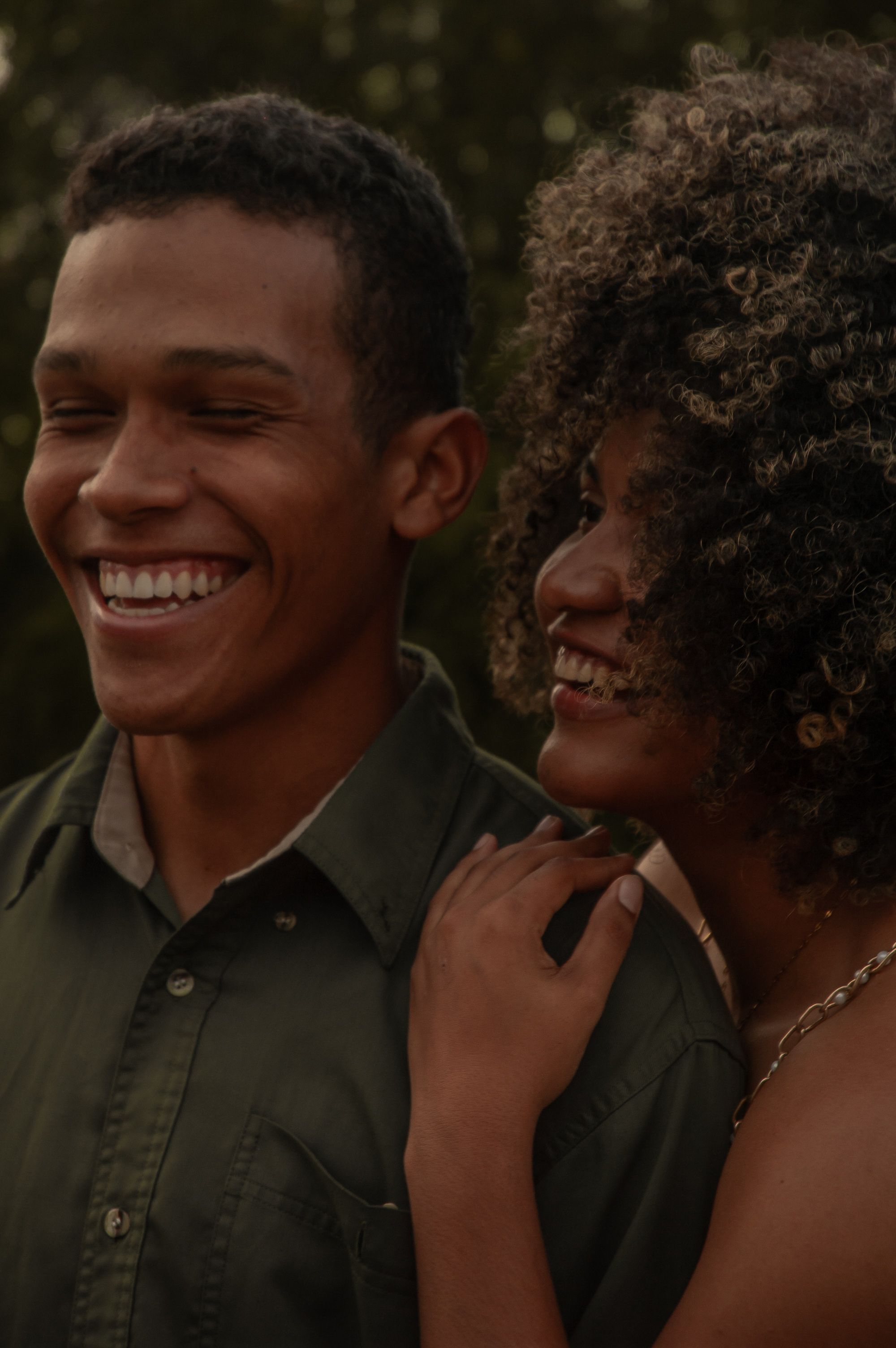 A happy young couple enjoying a laugh together outdoors. Warm tones create a cozy atmosphere.