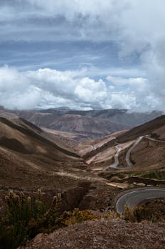 Curvy mountain road under a dramatic sky. Ideal for travel and adventure themes.