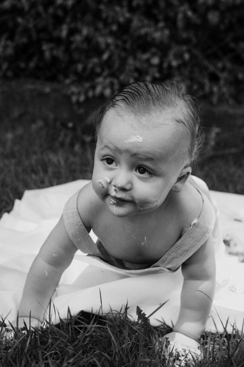 Free Charming black and white photo of a baby crawling outdoors on grass. Stock Photo