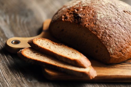 Free A close-up of rustic whole wheat bread with slices on a wooden board, creating a warm, artisanal feel. Stock Photo