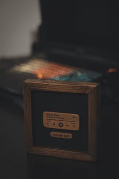Dark aesthetic wooden music display with vibrant laptop bokeh lights, creating a vintage-tech contrast.