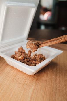 Chopsticks lifting sticky fermented soybeans from a white container, typical in Japanese cuisine.